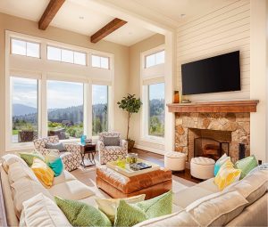 Living room with a sectional, ottoman, TV, and large windows with an expansive view