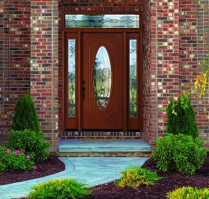 Brick home with a pathway that leads to a brown front entry door with glass inserts